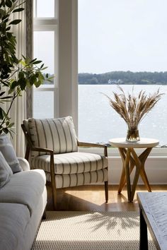 a living room filled with furniture and a large window overlooking the water's edge