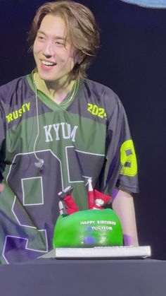 a young man standing in front of a cake