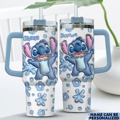 two blue and white tumblers with cartoon characters on them sitting next to a plant