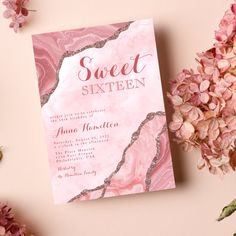 a pink and silver marbled sweet sixteen party card on a table next to flowers