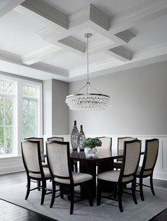 a dining room table with chairs and a chandelier hanging from it's ceiling