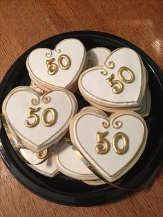 decorated cookies in the shape of heart shaped numbers on a black plate with gold trim