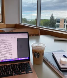 an open laptop computer sitting on top of a table next to a cup of coffee