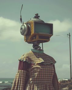 a woman with a camera on her head standing in front of the ocean and looking into the distance