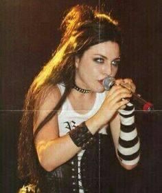 a woman with long hair holding a microphone in her hand and wearing black and white striped stockings