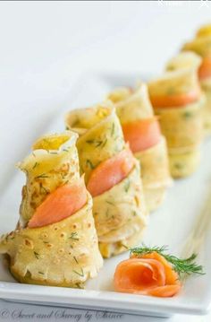 small appetizers are arranged on a white plate with carrots and dill