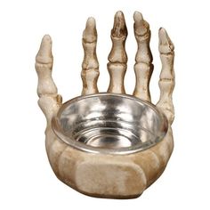 an animal's skeleton hand holding a silver bowl