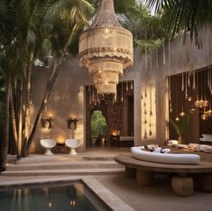 a room with a pool and chandelier hanging from it's ceiling, surrounded by palm trees