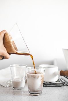 a person pouring something into two glasses