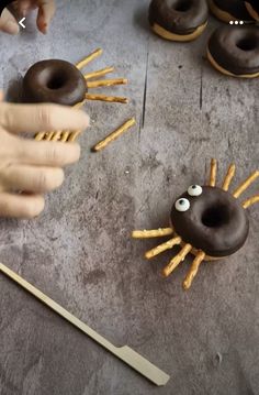 two donuts with eyes and arms made to look like spider legs are being held by someone's hand