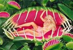 a woman laying on top of a giant pink flower surrounded by green leaves and flowers