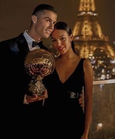 a man and woman pose with their trophies in front of the eiffel tower