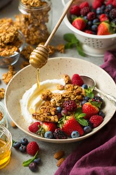 a bowl filled with yogurt, berries and granola on top of a table