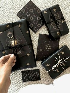 a person holding a wrapped gift in front of some black and gold wrapping paper on top of a table