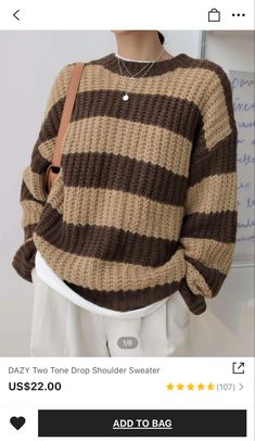 a woman wearing a brown and black striped sweater with white shorts on the bottom is looking at