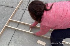 a woman in pink shirt standing on top of a wooden frame