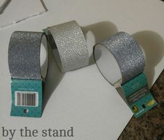 two rolls of silver glitter tape on top of a white box with a barcode