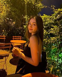 a beautiful young woman sitting at an outdoor table