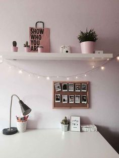 a white desk with some pictures on it and lights strung from the wall above it