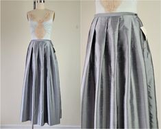 "Vintage 1980's, formal silver/gray long skirt with large pleats at the waist. Beautiful, shiny material resembles dupioni silk. Sits high on the waist, lightweight and comfortable material. Zipper and button on the side, unlined. Machine wash. Small New, and unworn old stock. Excellent condition Nylon 54%, Poly 46% Made by FIRST ISSUE PETITES A LIZ CLAIBORNE COMPANY M E A S U R E M E N T S Waist 26\" Length 38\" Hips / Free Measurements are of the item while laid flat and doubled where appropriate. Please make accommodations in the measurement for movement and desired comfort." Metallic Pleated Evening Skirt, Dupioni Silk, Full Skirt, Long Skirt, Pleated Skirt, Maxi Skirt, High Waisted Skirt, Womens Skirt, Ball Gowns