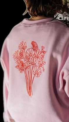 the back of a woman's pink sweatshirt with red flowers on it and long sleeves