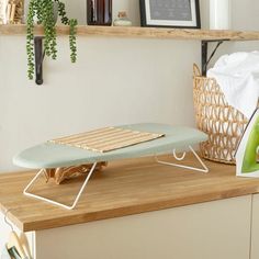 a ironing board sitting on top of a wooden counter next to a basket with clothes