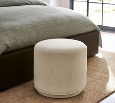 a white ottoman sitting on top of a carpeted floor next to a large bed