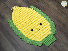 a crocheted yellow and green rug with a smiling face on it's side