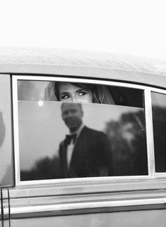 a black and white photo of a woman in a car looking out the window