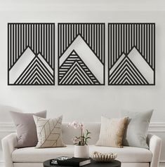 two black and white paintings on the wall above a couch in a modern living room