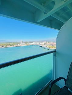 a balcony with a view of the water and buildings in the distance, looking out over the ocean