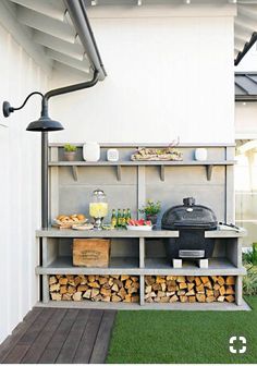 an outdoor bbq with lots of wood stacked on the shelves and grilling area