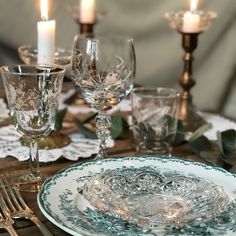 a table set with plates, silverware and candles