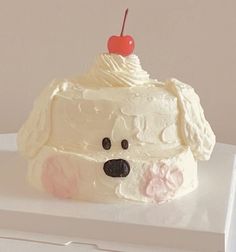 a cake shaped like a dog with a cherry on top is sitting on a white surface