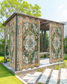 an artisticly designed outdoor shelter in the middle of a grassy area with stone walkways