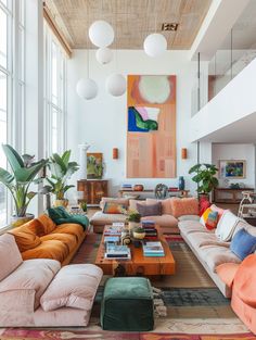 a living room filled with lots of furniture and large paintings on the wall above it