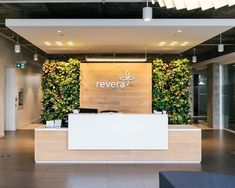 an office lobby with plants growing on the wall and reception desk in front of it