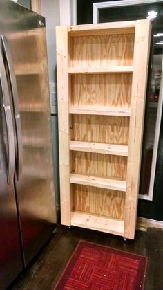 a wooden shelf next to a refrigerator in a kitchen with a red rug on the floor