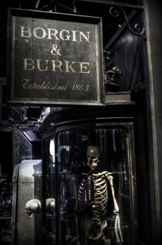 a skeleton is standing in front of a sign that says borrn & burke