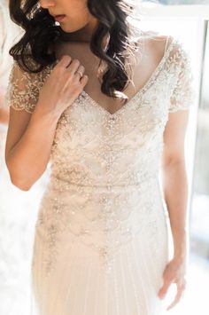 a woman in a wedding dress adjusting her collar