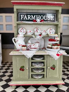 an old fashioned dollhouse kitchen with plates and cups on the counter, including strawberry shortcakes