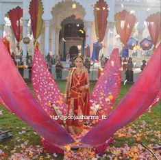 a woman in a red and gold dress standing under an elaborately decorated flower arrangement