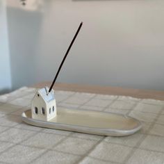 a small white house sitting on top of a plate with a stick sticking out of it