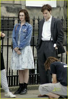 a man and woman standing next to each other in front of a black iron fence