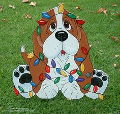 a brown and white dog with christmas lights on it's face sitting in the grass