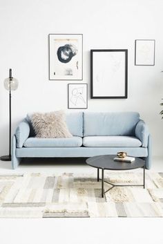 a living room with a blue couch, coffee table and pictures on the wall above it