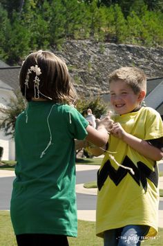 two young boys playing with a kite in the grass