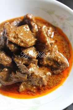 a white bowl filled with meat covered in gravy