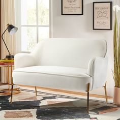 a white couch sitting on top of a rug next to a window