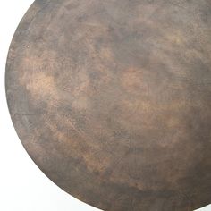 a round metal table with brown pattered paint on the top and bottom surface, against a white background